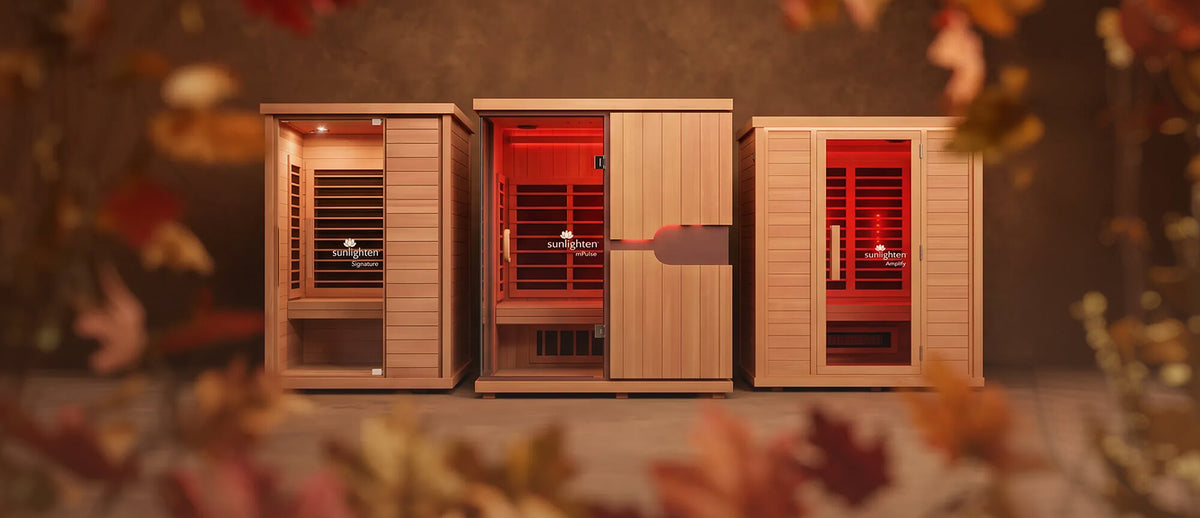 Three Sunlighten cabin saunas shown against a autumn backdrop surrounded by leaves.